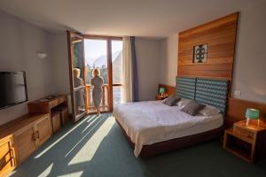 a bedroom with a bed and a tv and a person looking out the window at Hotel Boka in Bovec