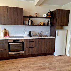 a kitchen with wooden cabinets and a sink and a refrigerator at Olga Apartments in Grundarfjordur