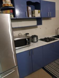a small kitchen with blue cabinets and a microwave at Apartments for short stay in Ashalebotwe