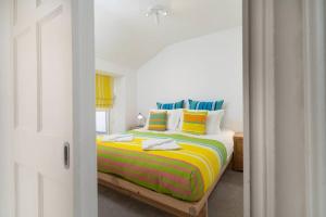 - une chambre avec un lit doté de draps et d'oreillers colorés dans l'établissement Beautiful and Contemporary Cornish townhouse in Penzance, à Penzance