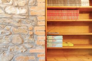 un estante de libros junto a una pared de piedra en Appartamento La facciavista, en Pian di Scò
