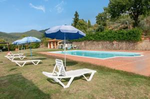 2 Stühle und Sonnenschirme neben einem Pool in der Unterkunft Appartamento La facciavista in Pian di Scò
