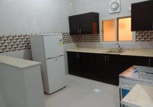 a kitchen with a white refrigerator and black cabinets at الحمدانية الراقي للأجنحة الفندقية in Jeddah