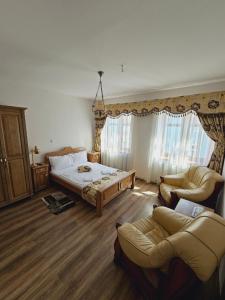 a bedroom with a bed and two chairs in it at Pensiunea Nobil Medieval in Sighişoara