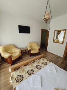 a living room with a bed and two chairs and a tv at Pensiunea Nobil Medieval in Sighişoara