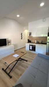 a living room with a table and a kitchen at Studio rénové centre-ville de Lagnieu / WIFI in Lagnieu