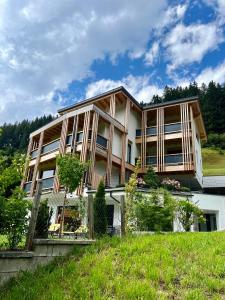a large house on top of a green hill at Natur Zeit - Alpine Garden Apartments in Mayrhofen