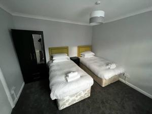 two beds in a small room with white sheets at Cosy 2-bed Town House In Central Brighton Sleep 4 in Brighton & Hove