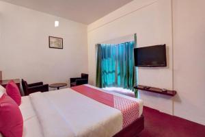 a hotel room with a bed and a television at Ooty Residency in Ooty