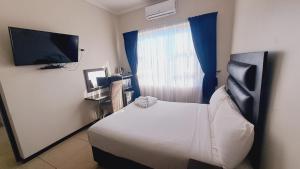 a bedroom with a bed and a flat screen tv at Bayside Hotel Empangeni in Empangeni
