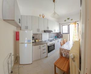 cocina con armarios blancos, mesa y nevera en Like HomeRetro Central Apartment, en Tríkala