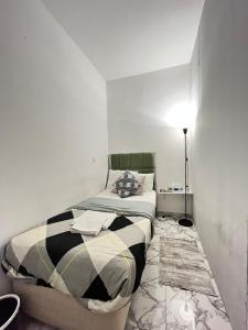 a small bedroom with a bed and a lamp at Tanih Place in Abu Dhabi