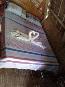 uma cama com um cisne em cima em KOKONUT HUT RETREAT & CAMPING SITE RENTAL em Romblon