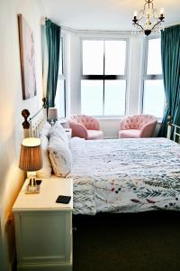 Glan y Mor, Sleeps 20, 8 Bedrooms, 8 Bathrooms, Seafront, Criccieth في كريسيث: غرفة نوم بسرير وطاولة وكرسيين