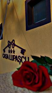 a sign on a wall with a rose in front of it at Casa Lupascu in Vatra Dornei