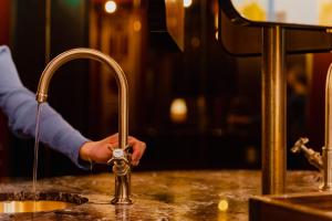 a man is washing his hands under a kitchen faucet at Hotel Mai Amsterdam in Amsterdam