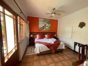 Schlafzimmer mit orangefarbenen Wänden und einem Bett mit roten Kissen in der Unterkunft Marula Lodge in Swellendam