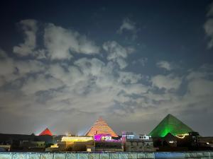 uma vista das pirâmides de giza à noite em mesho falcon Pyramids view inn no Cairo