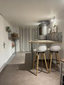 a kitchen with a table and two bar stools at Appartement T1 renové in Gigean