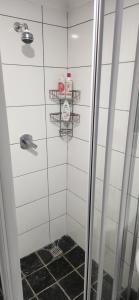 Un baño con ducha con azulejos blancos. en Die Huisies, en East London