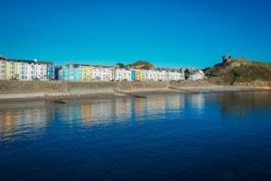 a large body of water with buildings in the background at Glan y Mor, Sleeps 20, 8 Bedrooms, 8 Bathrooms, Seafront, Criccieth in Criccieth