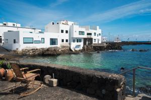 a white building with a chair and the water at Lanzahost Villa Mimosa in Punta de Mujeres