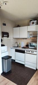 a kitchen with white cabinets and a stove top oven at Sunny Snow Studio les Orres 1650 in Les Orres