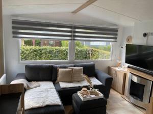 a living room with a couch and a large window at Stijlvol Chalet Lathum in Lathum