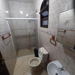 a bathroom with a shower and a toilet and a sink at Pousada Morada dos Pássaros in Peruíbe