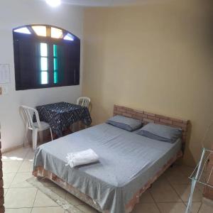 a bedroom with a bed and a table and a window at Pousada Morada dos Pássaros in Peruíbe