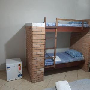 a room with two bunk beds in a brick wall at Pousada Morada dos Pássaros in Peruíbe