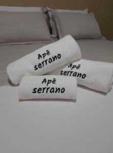 Tres toallas blancas en una cama con las palabras serrano en Apê Serrano en Serra de São Bento