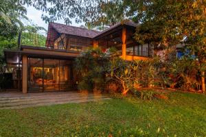 a house with glass doors and a yard at StayVista at Toya Toya River View in Kozhikode