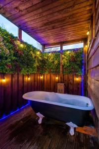 a large bath tub in a wooden bathroom with lights at The Shepherds Retreat - Ockeridge Rural Retreats in Wichenford