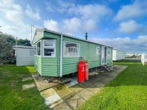 a green caravan with two fire hydrants in a yard at Homely Dog Friendly Caravan At California Cliffs Holiday Park, Ref 50024j in Great Yarmouth