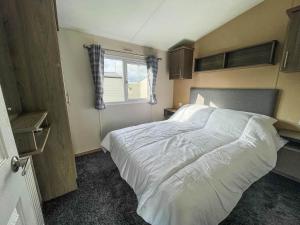 una camera con un letto bianco e una finestra di Homely Dog Friendly Caravan At California Cliffs Holiday Park, Ref 50024j a Great Yarmouth