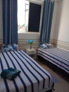 - 2 lits dans une chambre avec des rideaux bleus et une fenêtre dans l'établissement Pedacinho de Lar, à João Pessoa