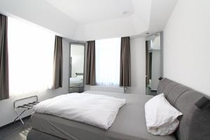 a bedroom with a bed and a couch and windows at Hotel Mennicken in Würselen