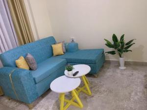 a living room with a blue couch and a table at Roses Suites in Nairobi
