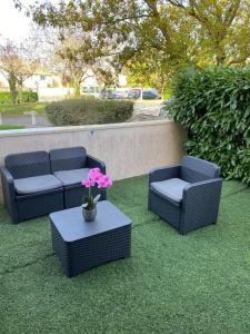 3 chaises et une table avec des fleurs sur l'herbe dans l'établissement Logement entier chambre+salon + jardin & terrasse, aux Ulis