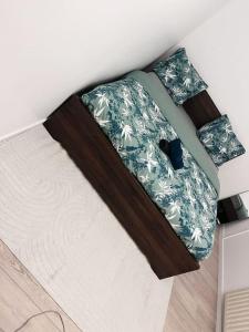 - un lit avec une couverture verte et blanche dans l'établissement Logement entier chambre+salon + jardin & terrasse, aux Ulis