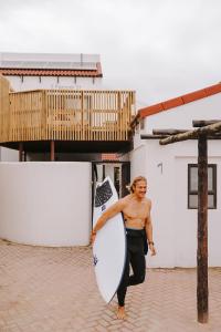 a woman is holding a surfboard in front of a building at 7 Pepper Street by African Perfection in Jeffreys Bay