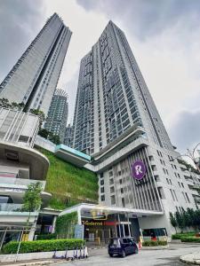 a tall building with a purple sign on it with two tall buildings at Moderno Luxury Suite@Robertson Kuala Lumpur in Kuala Lumpur