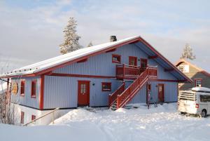 una casa azul con puertas rojas en la nieve en Idre Fjäll, Söderbyn Ski in Ski out, 30 m till pisten en Idrefjäll