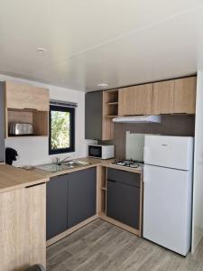 a kitchen with a white refrigerator and wooden cabinets at Camping Les P'tites Maisons dans la Prairie in Sallertaine