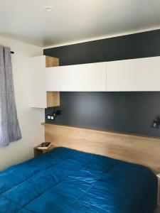 a bedroom with a blue bed and white cabinets at Camping Les P'tites Maisons dans la Prairie in Sallertaine