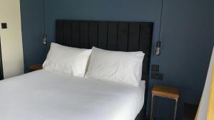 una camera da letto con letto, lenzuola e cuscini bianchi di Park Lane Rooms ad Abergavenny