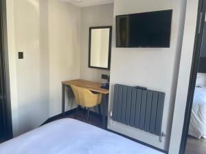 - une chambre avec un bureau, une télévision et un lit dans l'établissement Park Lane Rooms, à Abergavenny