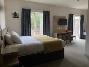 Dormitorio con cama, escritorio y TV en The Lodge At Perth Racecourse en Perth
