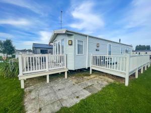 a blue tiny house with a white fence at Stunning Dog Friendly Caravan At Manor Park, Hunstanton In Norfolk Ref 23188k in Hunstanton